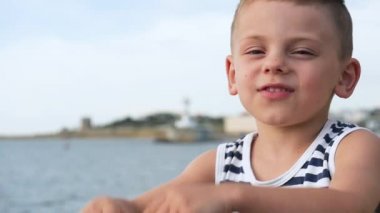 Yaz aylarında deniz arka plan üzerinde çizgili gömlekli mutlu küçük çocuk