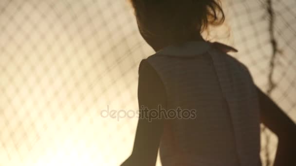 Schattige jongen en meisje springen op de trampoline bij zonsondergang — Stockvideo