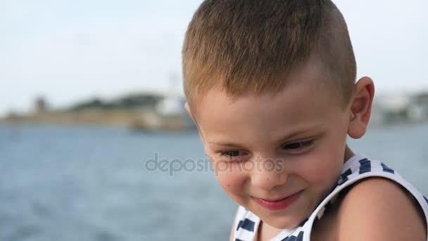 Мальчик в полосатой рубашке с биноклем перед морем — стоковое видео