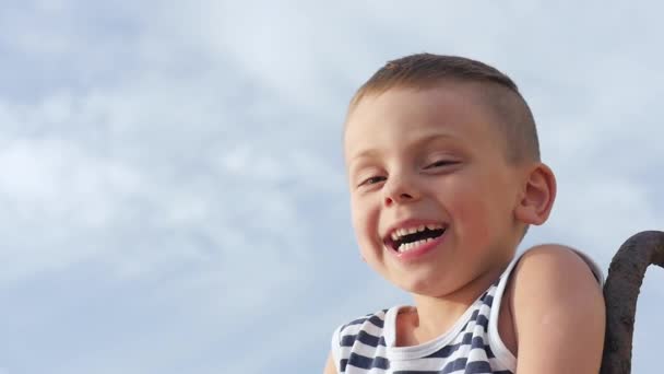 Милый мальчик смеется и улыбается на фоне неба — стоковое видео