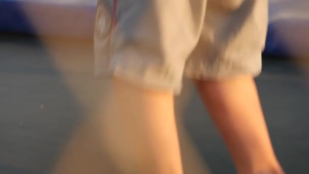 Benen van kleine jongen en meisje lopen en springen op de trampoline — Stockvideo