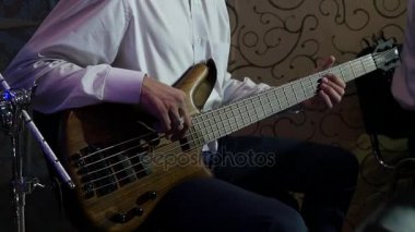 Çerçeve bas gitar oyuncu yakın çekim merkezi bir canlı konser oynayan beyaz gömlekli müzisyen elleri