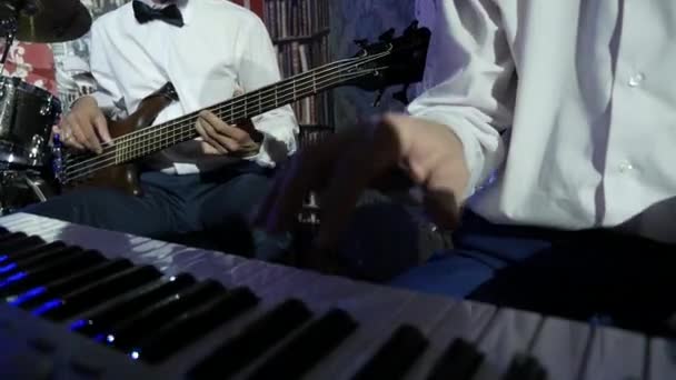 手中的音乐家在白色的衬衫演奏现场演唱会 用右手的男性手弹奏电子琴在低音吉他弹奏者的中心左边鼓集合 爵士乐乐队在音乐厅 — 图库视频影像