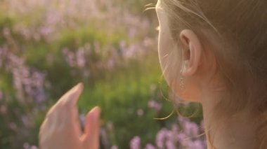 genç kız el Close-Up saç modeli açık havada akşam lavanta çiçekleri ile alanında olurken düzeltir