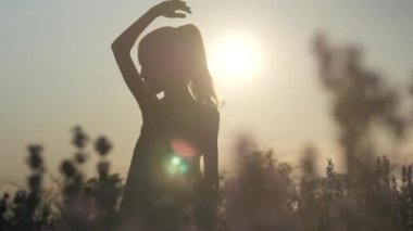 zarif siluet doğada küçük kız, başının üzerinde el, günbatımında kontur ışık