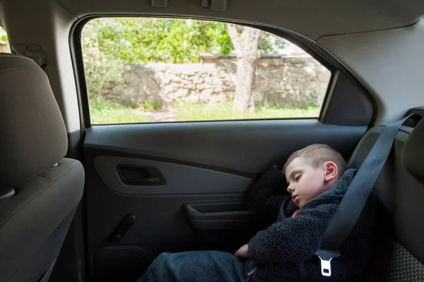 Mignon petit garçon dormir sur le siège arrière de la voiture — Photo