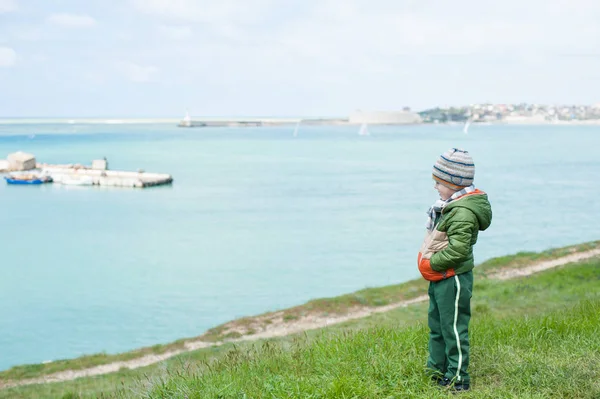 Μοναχικό αγόρι με σακάκι και καπέλο στέκεται στην πλαγιά φόντο της θάλασσας άνοιξη — Φωτογραφία Αρχείου