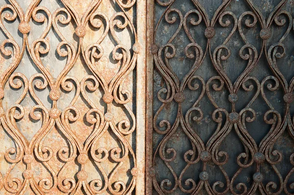 Rusty old wrought iron gates half-illuminated by the sun — Stock Photo, Image