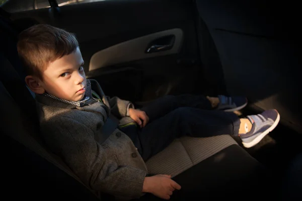 Triste garçon avec ceinture de sécurité assis sur le siège arrière d'une voiture — Photo