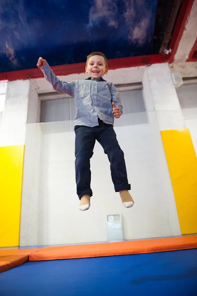 Felice ragazzo carino saltando su un trampolino all'interno — Foto Stock