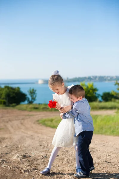 Komik küçük çocuk kız holding buket deniz arka plan bahar sarılma. — Stok fotoğraf