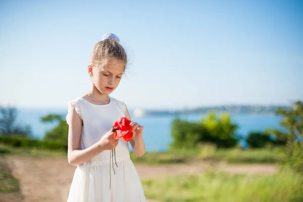 春の屋外手にオレンジ色の花に白いドレスでハンサムな女の子 — ストック写真