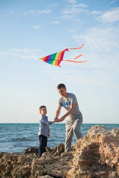 Baba ve oğul denizin kenarında uçurtma ilkbaharda denize indirmek — Stok fotoğraf