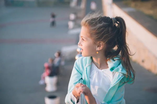 Mignonne petite fille souriante portant des outtoors chemisier turquoise au printemps au coucher du soleil — Photo