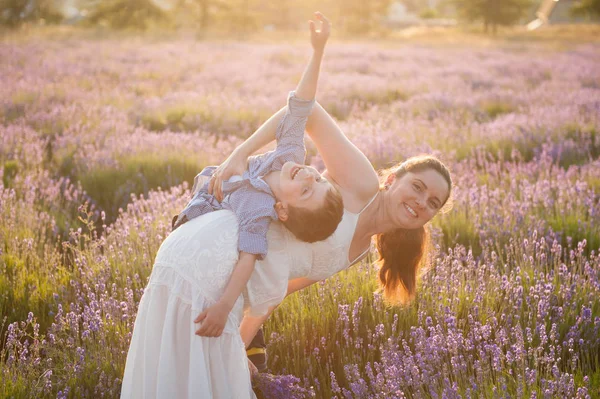 Bela mãe e criança brincando entre campos de lavanda no verão — Fotografia de Stock