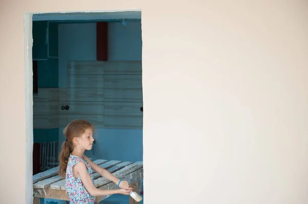 Menina pequena bonito no vestido de verão com uma parede de pintura escova na casa nova com espaço de cópia — Fotografia de Stock