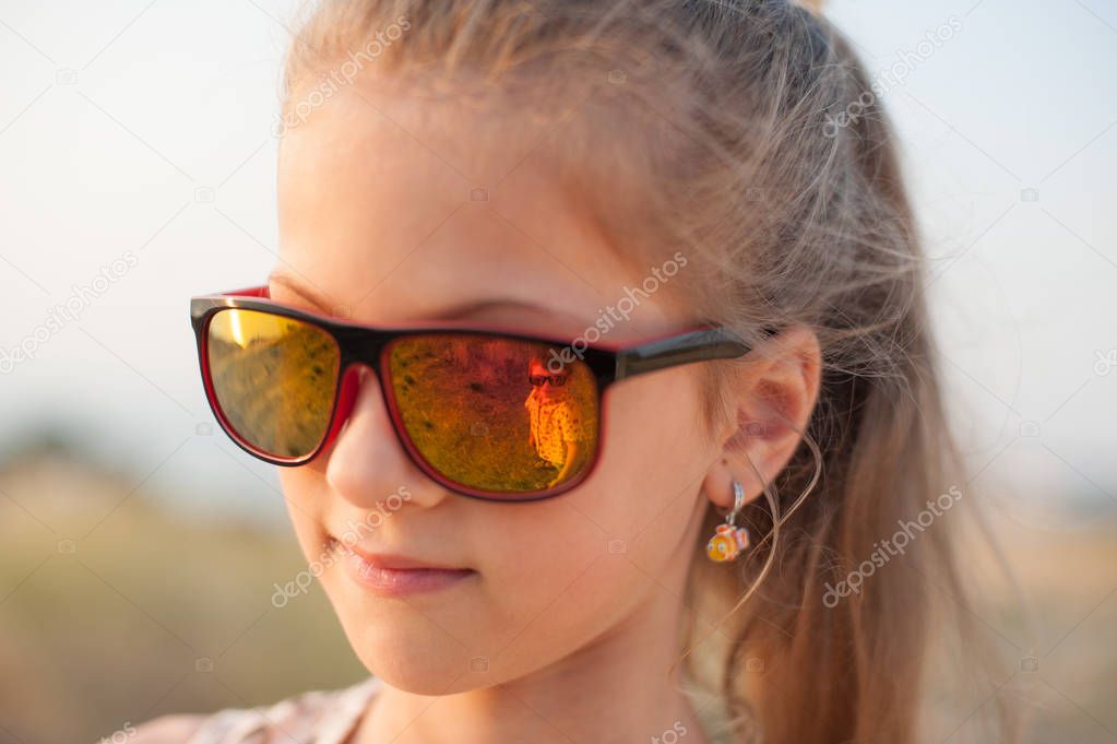 portrait of little cute girl in sunglasses with little boy reflected in them