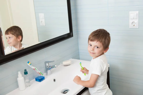 Hermoso niño pequeño con cepillo de dientes en la mano en el baño luminoso — Foto de Stock