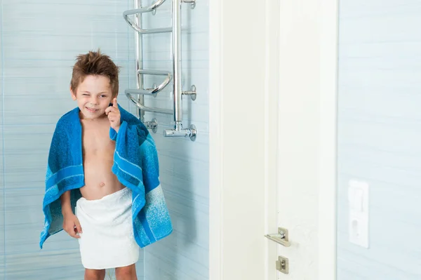 Vicces, aranyos kisfiú szempillantás állt egy törülközőt a fürdőszoba a vállára — Stock Fotó
