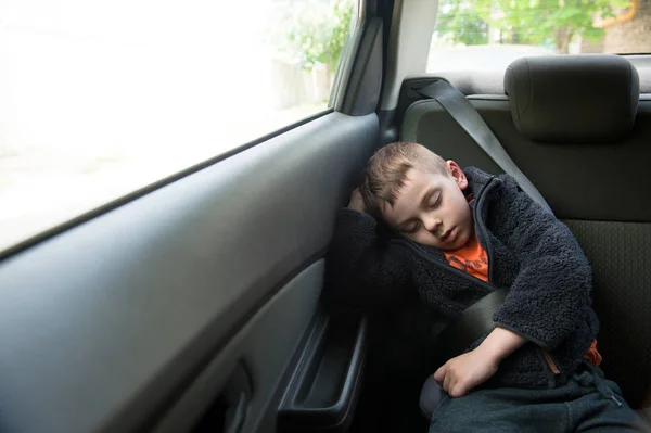 Dormir petit enfant assis dans la voiture dans le siège arrière avec ceinture de sécurité — Photo