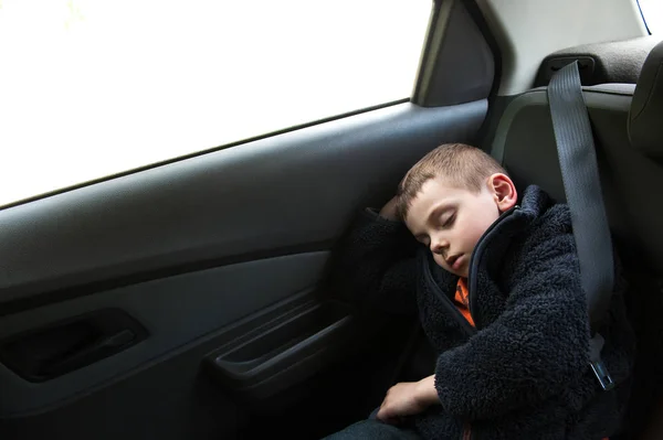 Petit enfant endormi assis dans la voiture dans le siège arrière avec ceinture de sécurité — Photo