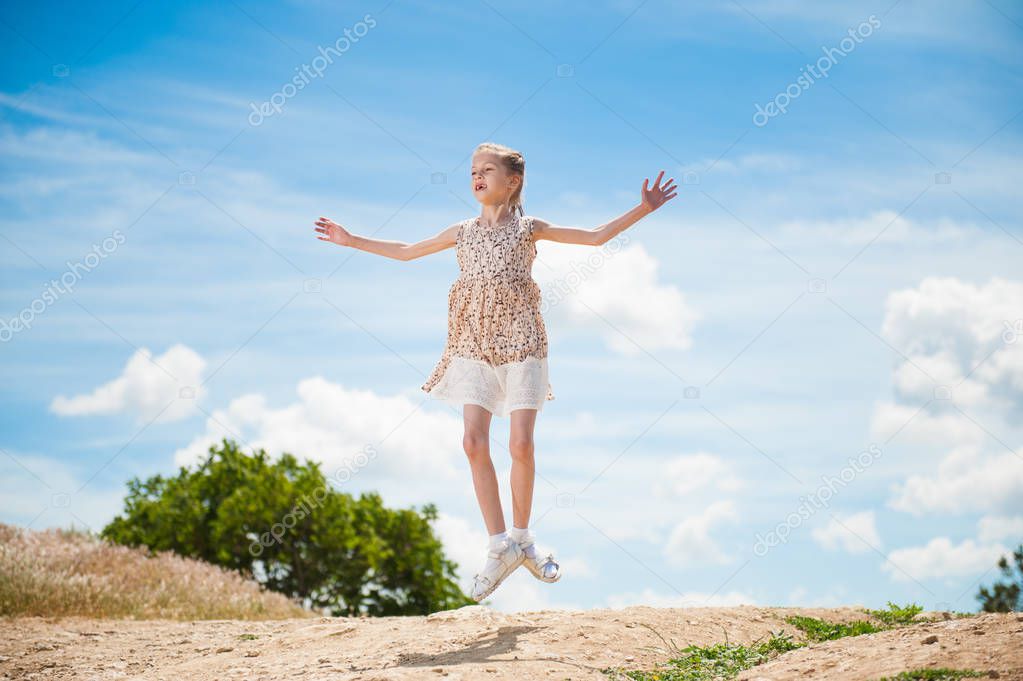 skinny beautiful dancer girl in dress jumping high against blue sky in summer