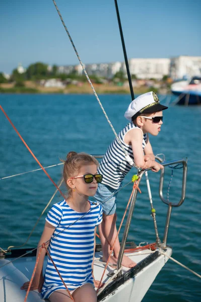Bellissimo ragazzo e ragazza in camicia a righe e occhiali da sole a bordo yacht bianco nel porto marittimo — Foto Stock