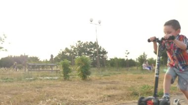 Sevinç mutluluk gün batımı yaz gülümseyen scooter Bahçesi sürme oynak küçük çocuk çok renkli gömlek