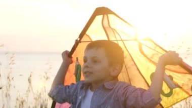rüya gibi küçük çocuk renkli uçurtma çim deniz kıyısı kafa onun ayakta günbatımı, sıcak yaz akşam yukarıda tutar
