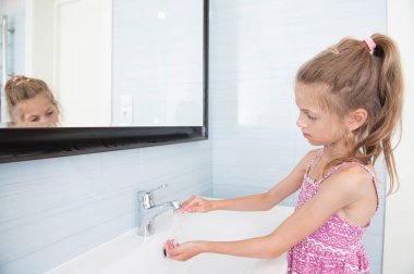 yakışıklı küçük kız elbiseli parlak banyo lavabo içinde ellerini yıkar