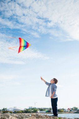 sevimli beyaz küçük çocuk oyuncak uçurtma yüksek Deniz Sahil resort yakınlarındaki mavi gökyüzünde uçan oynama