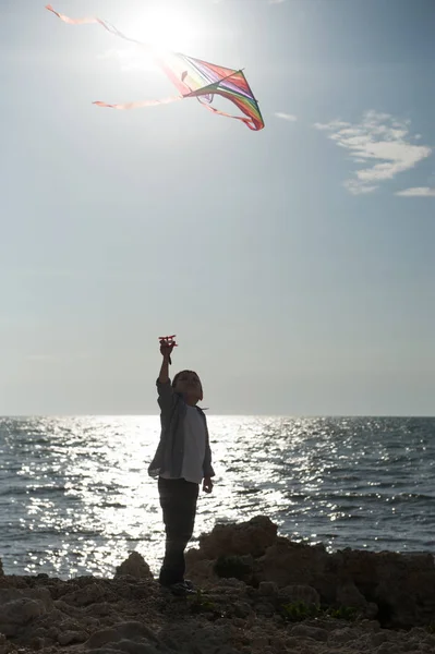 Σιλουέτα του μικρό παιδί εκμετάλλευση χαρταετό σε θάλασσα φόντο την άνοιξη — Φωτογραφία Αρχείου