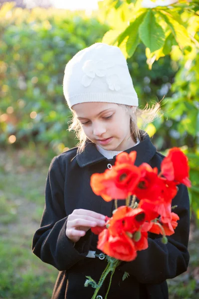 Belle petite fille en chapeau et manteau tenant bouquet de fleurs de pavot rouge au printemps — Photo