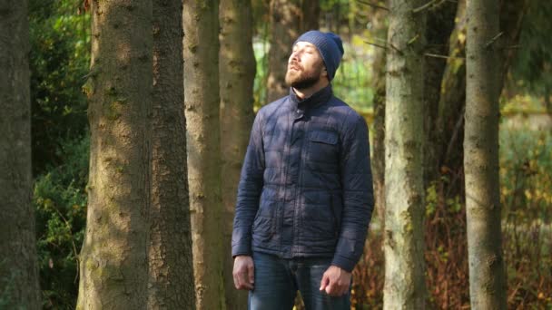 快乐的年轻人在城市公园里享受阳光 有胡子的男子站在外衣和针织帽室外 — 图库视频影像