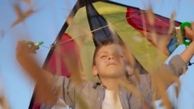 başını ve Rüzgar bekliyor üzerinden bir oyuncak uçurtma küçük çocuk çimlerin arasında ayakta tutan