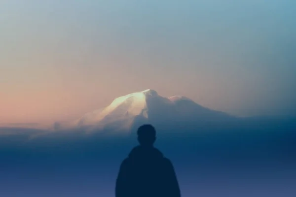 Homme silhouette randonneur se tient à l'extérieur en regardant plus haute montagne au coucher du soleil. concept nature et race humaine. espace de copie — Photo