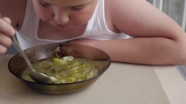 Şişman çocuk çocuk iştah ile çorba kavramı obez çocuk mutfakta, yiyor. -kadar yakın