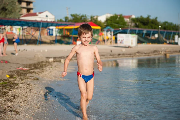 Petit enfant mignon en bonne santé courant le long de la côte sur la plage de vacances d'été sur la station — Photo