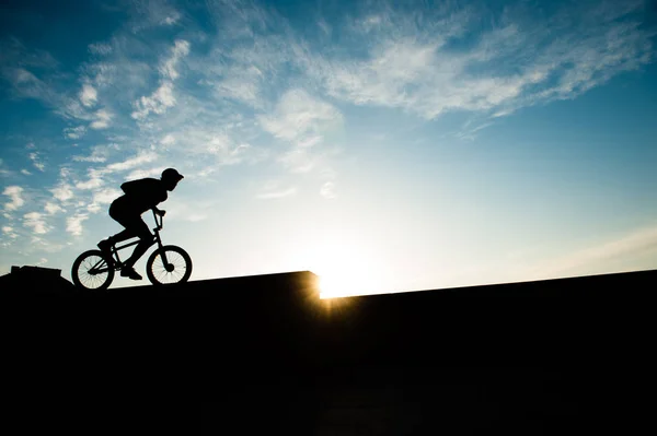 Extreme jongeman fietsten op zonsondergang achtergrond met copyspace — Stockfoto