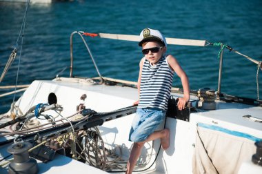 Küçük şirin çocuk yazın lüks bir yatta kaptan şapkası takıyor.