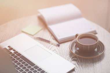 kompozisyon yaşam tarzı dizüstü, not defteri, kalem ve ahşap tabloda çay ile sıcak ışık yaktı