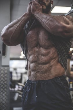 güçlü sakallı adam spor salonunda antrenman yapıyor.