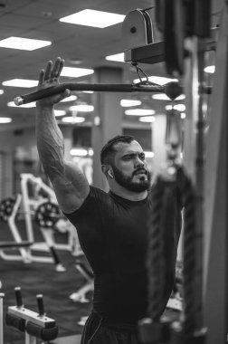 güçlü sakallı adam spor salonunda antrenman yapıyor.