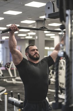 güçlü sakallı adam spor salonunda antrenman yapıyor.