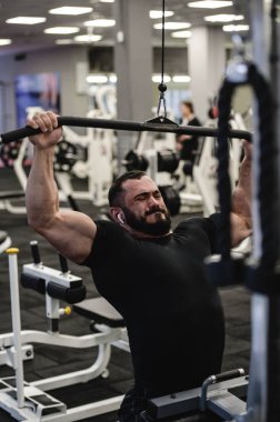 güçlü sakallı adam spor salonunda antrenman yapıyor.