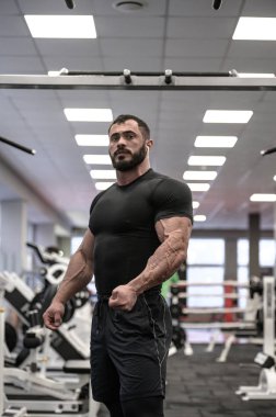 güçlü sakallı adam spor salonunda antrenman yapıyor.