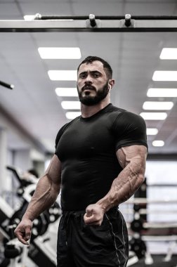 güçlü sakallı adam spor salonunda antrenman yapıyor.