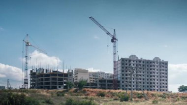 Cranes no longer work on Construction Site outdoor sunny day. tall cranes stand motionless against background floating clouds blue sky .work stopped result economic crisis.