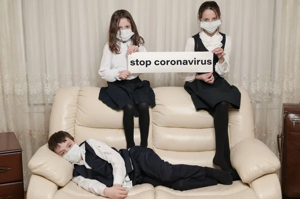学校の制服を着た3人の病気の子供のコロナウイルス発生概念家に座っているコロナウイルスを停止します — ストック写真