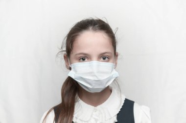 Coronavirus covid-19 salgın hastalık sağlık hizmetleri konsepti. Tıp maskesi takan ve okul üniforması giyen küçük güzel bir kız.